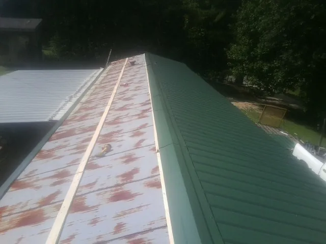 Old rusted panels beside newly installed green metal roofing — Wind Damage Roof Repair by Roofing Brothers in Hampstead