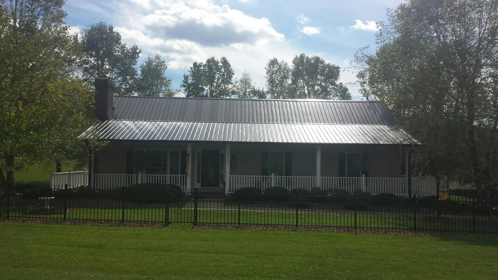 Gray metal roof on a brick ranch with a full width front porch — Gutter Guard Installation work by our crew in Hampstead